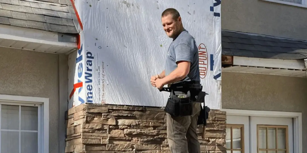 An HRS exterior repair expert installing Versetta Stone on a house in Pelham, AL