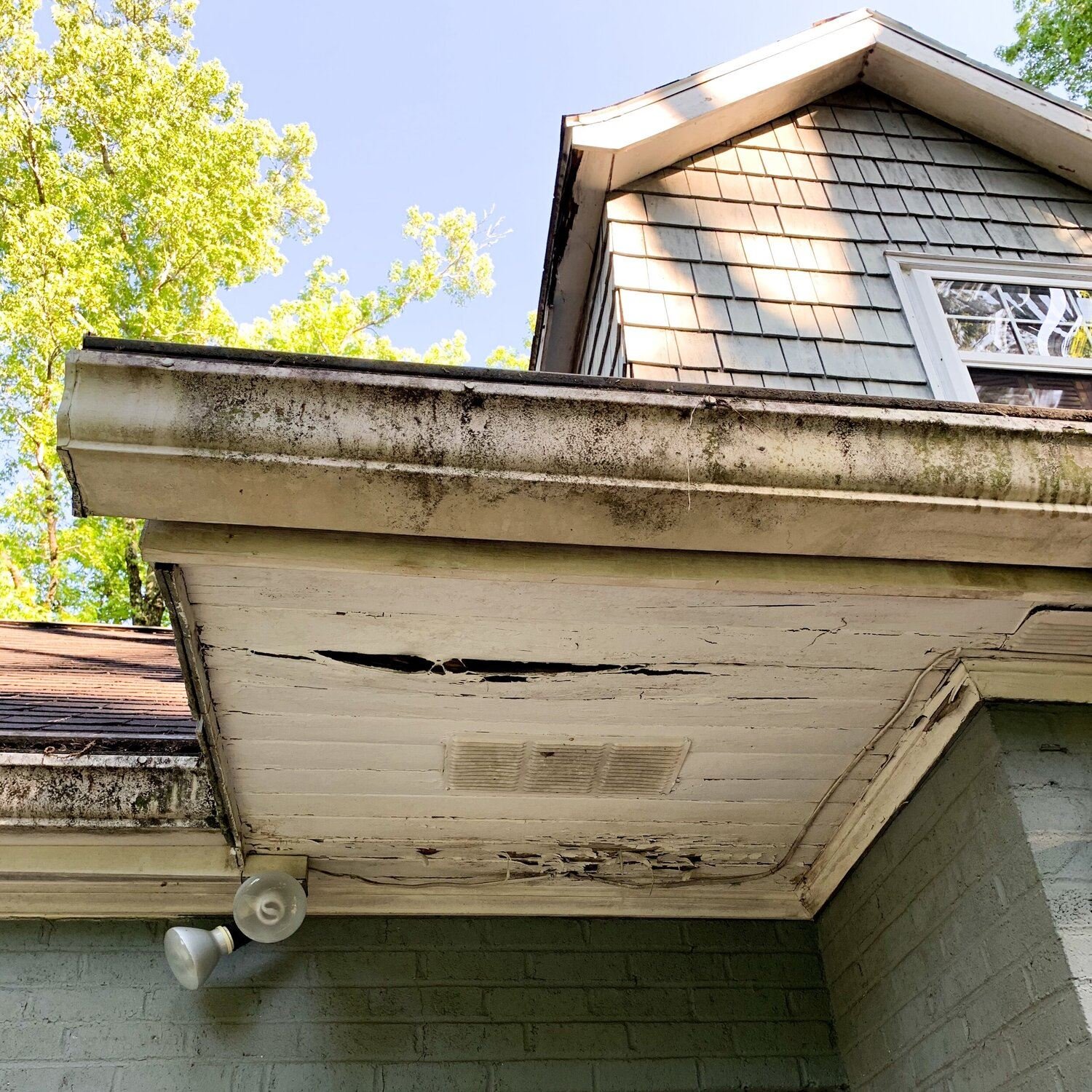 A home with rotten soffits caused by overflowing gutters