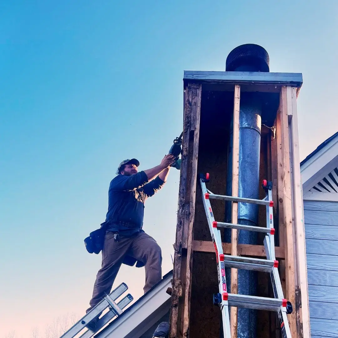 A home exterior contractor removing rotten Masonite siding from a chimney in Pelham, AL.