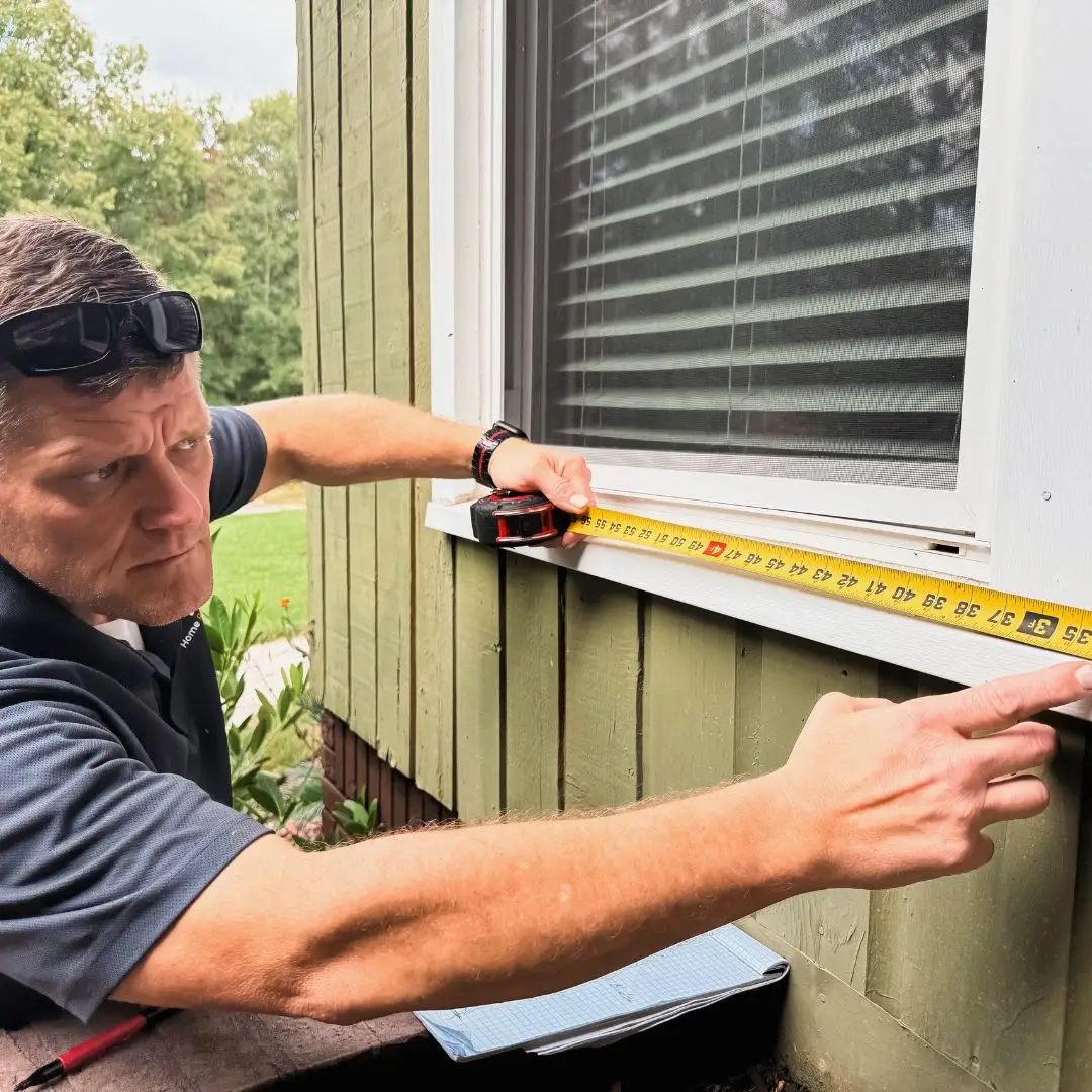 An HRS exterior handyman measuring a window in Hoover.
