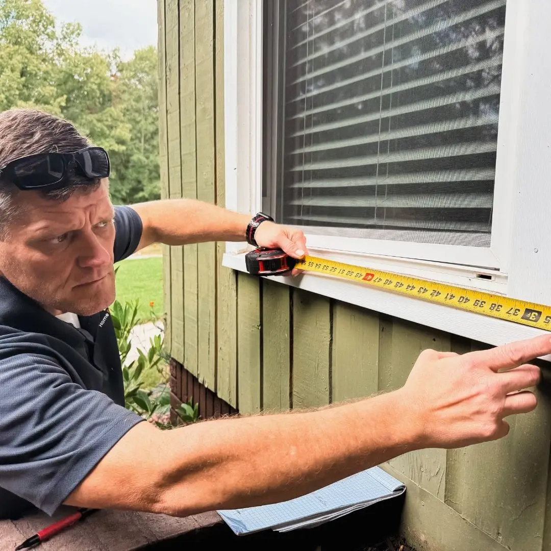 An HRS window contractor measuring a window.