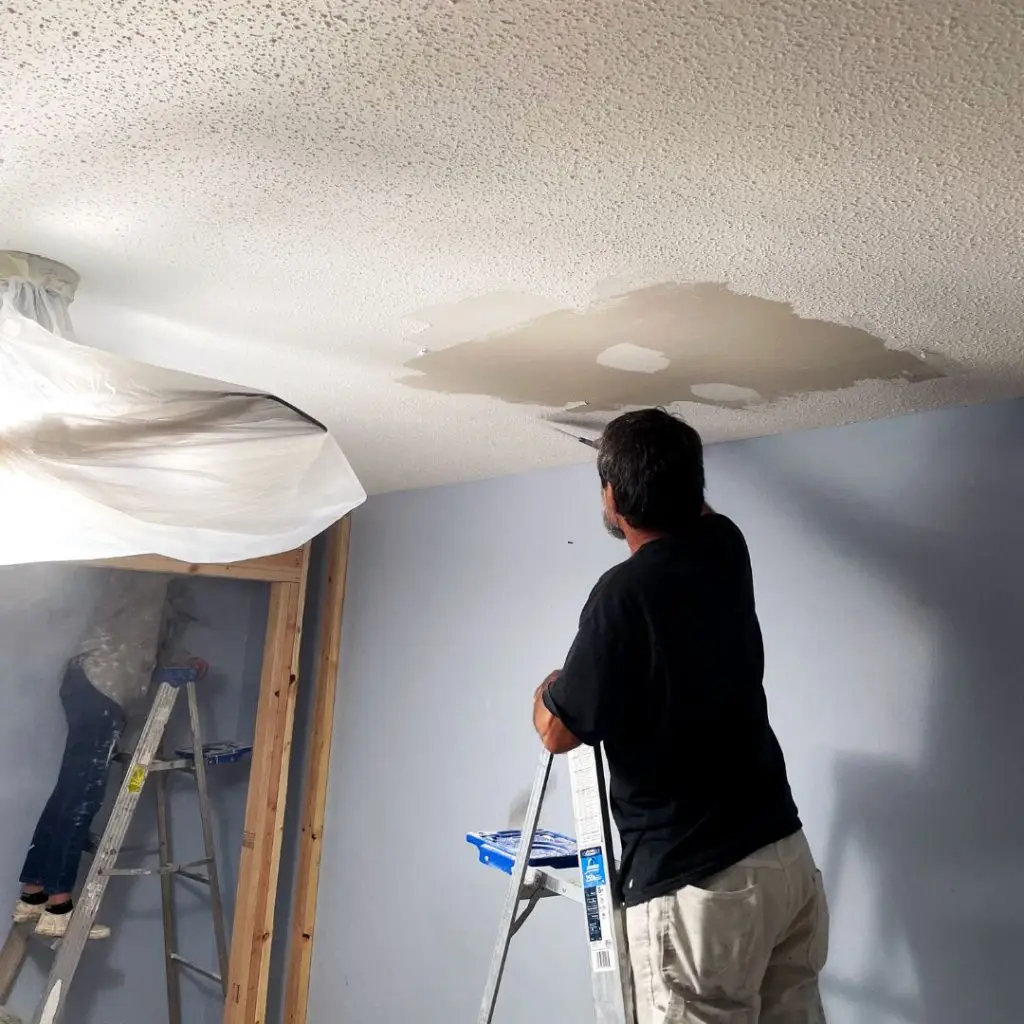 An interior painting contractor removing popcorn ceiling texture from a room in Hoover, AL.