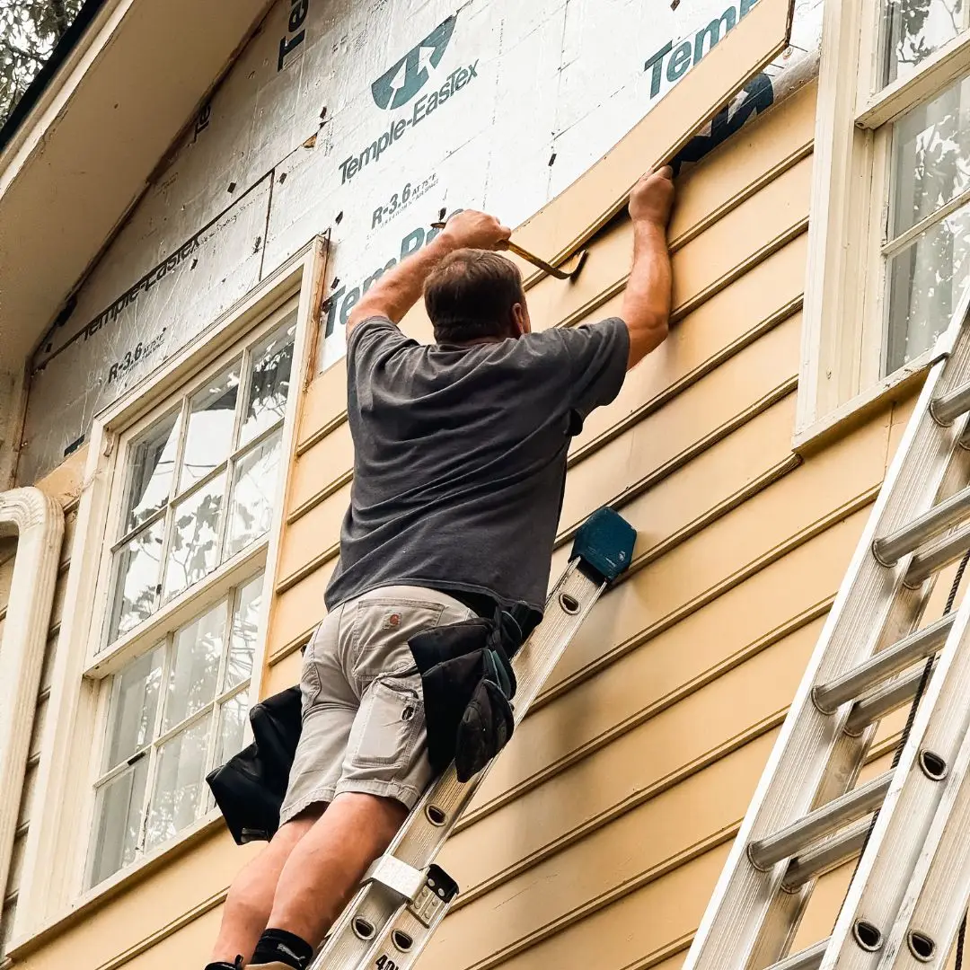 A man replacing the siding on a house in Hoover, AL.