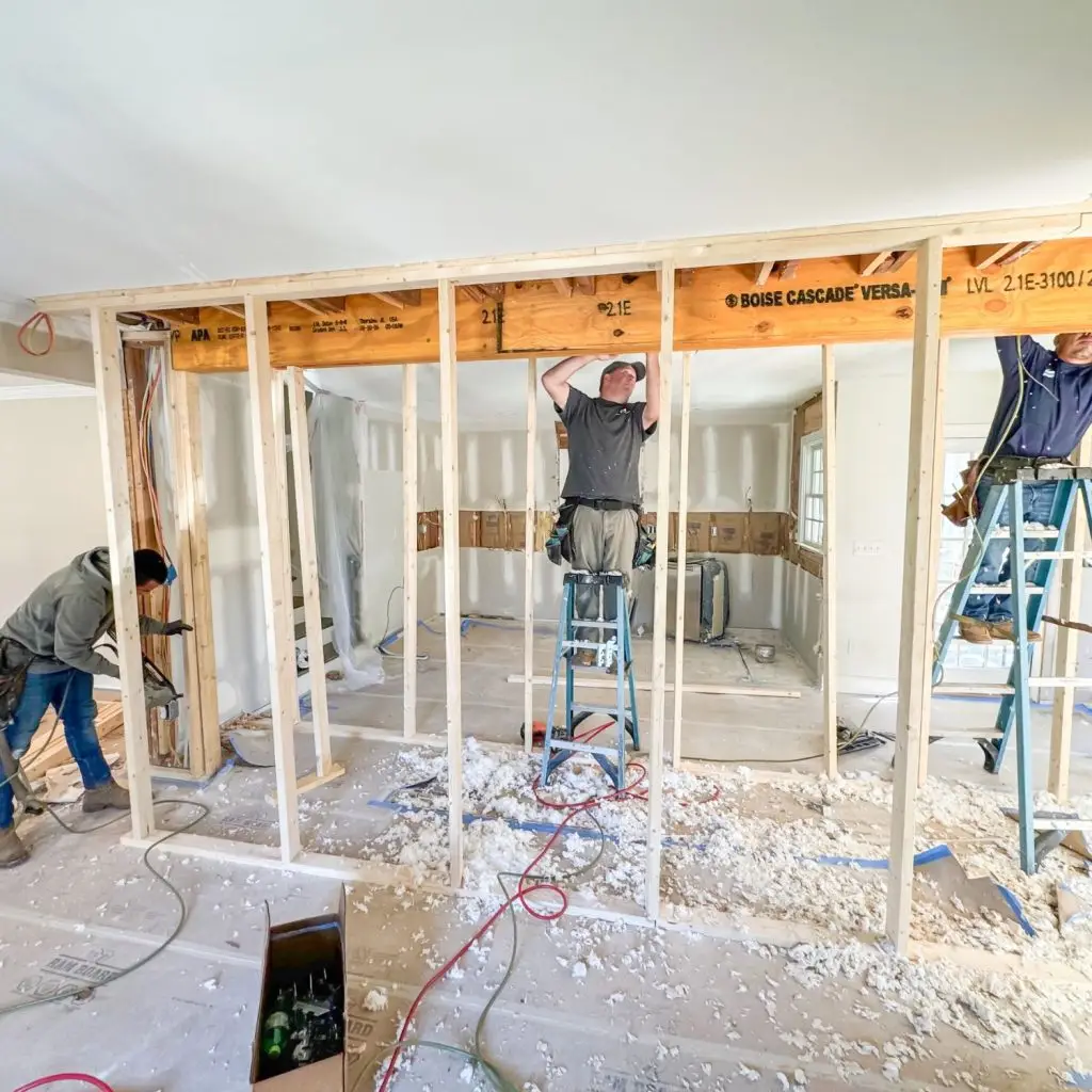A construction team removing a load-bearing wall, a critical step in transforming a closed-off kitchen into an open and functional space.