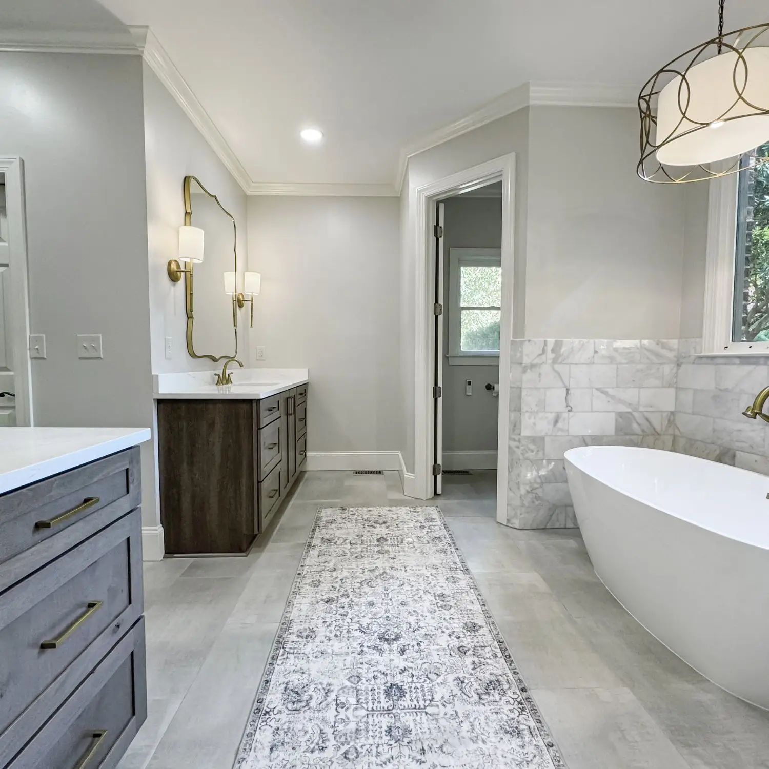 A beautiful bathroom renovation on Thompson Road in Alabaster featuring a freestanding tub, double vanity, and elegant lighting.