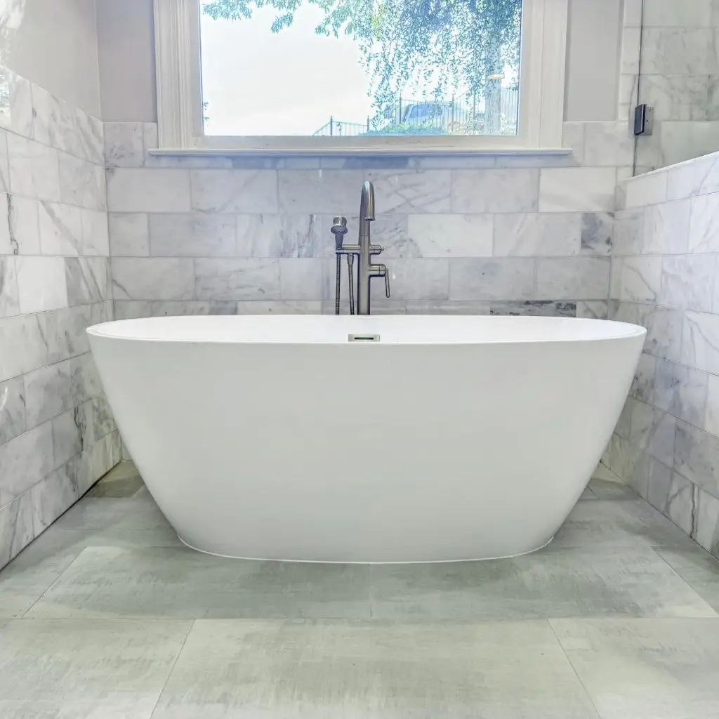 A sleek freestanding tub with a modern floor-mounted faucet, with premium tile adding to the overall remodel cost.