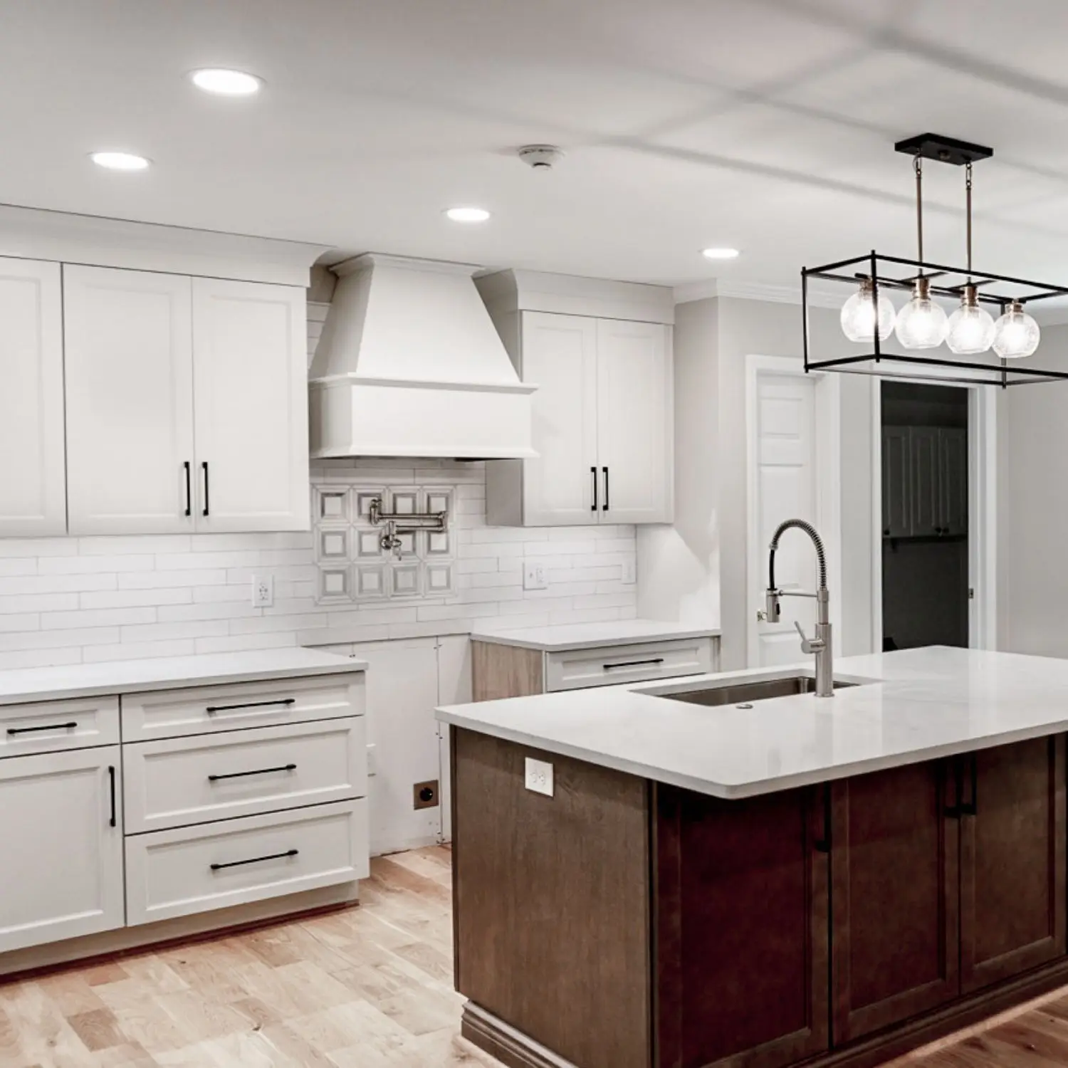 A stylish kitchen remodel in Alabaster, AL with white cabinetry, a modern island, and sleek pendant lighting.