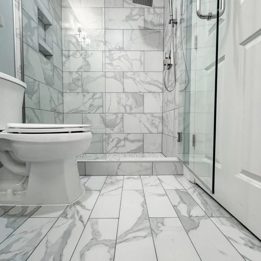 This bathroom remodeling in Hoover features a sleek glass-enclosed shower, marble tile, and modern fixtures for a clean, updated look.