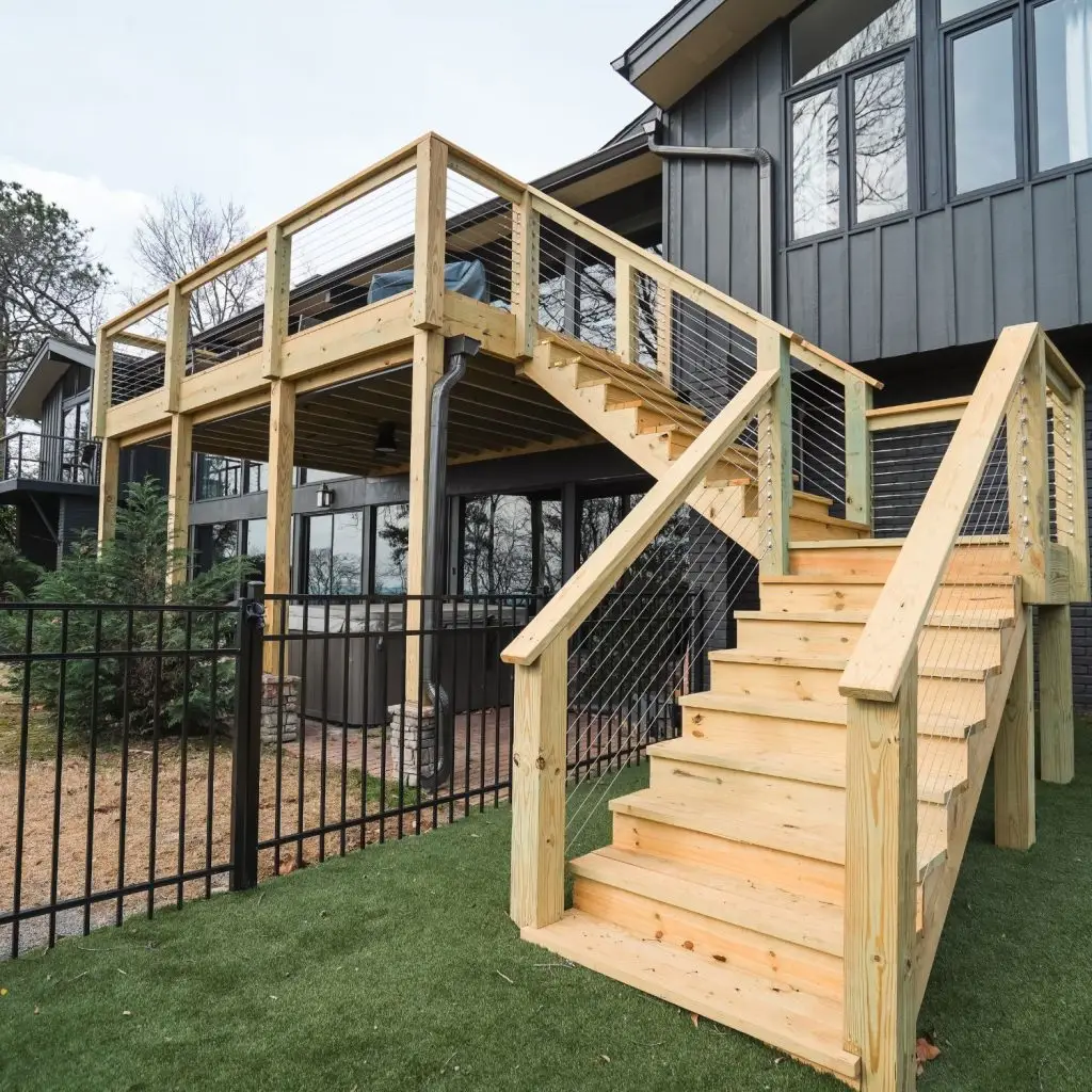 A professionally built elevated wood deck with cable railing and wide stairs, illustrating the cost to build a 20x20 wood deck in a modern residential setting.