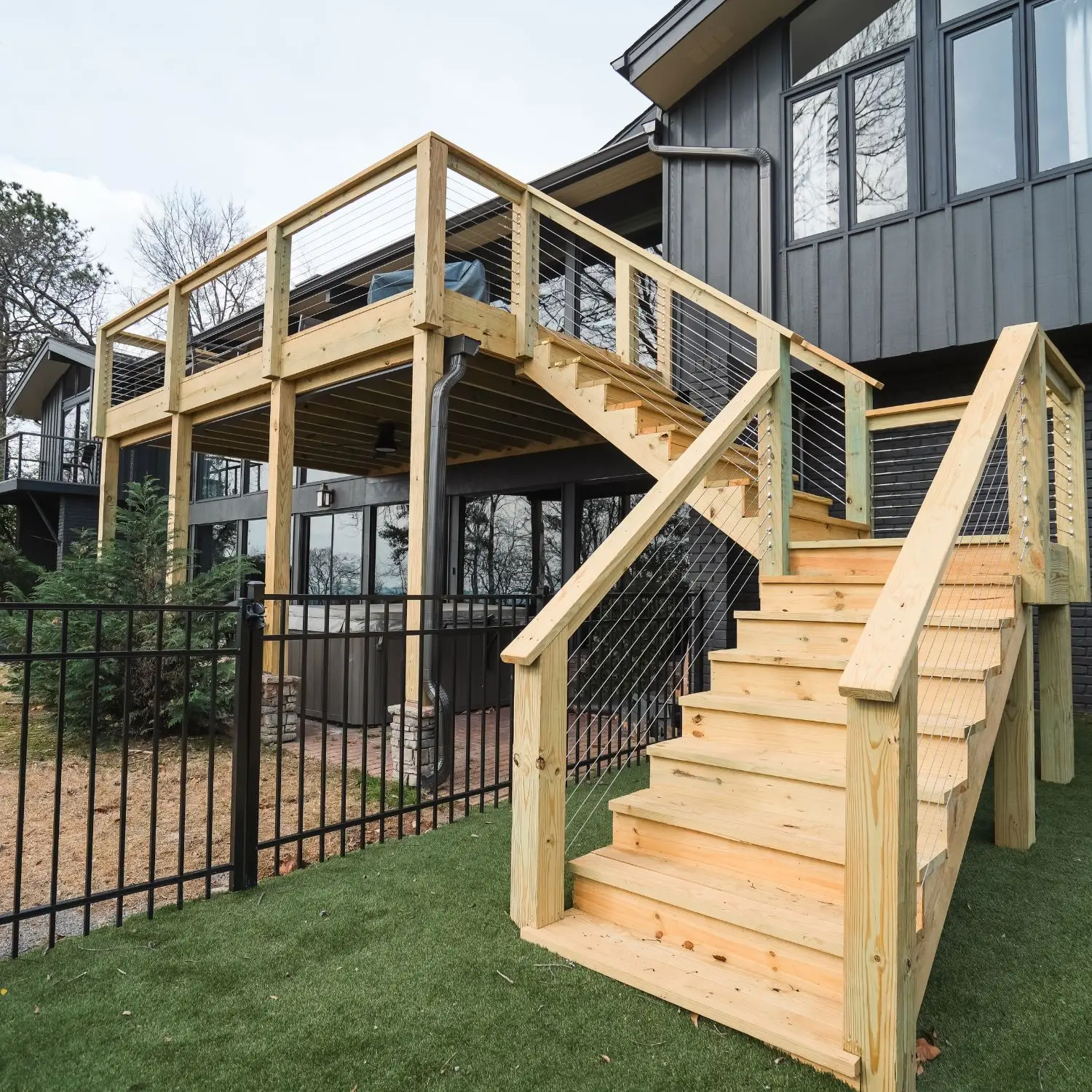 A professionally built elevated wood deck with cable railing and wide stairs, illustrating the cost to build a 20x20 wood deck in a modern residential setting.