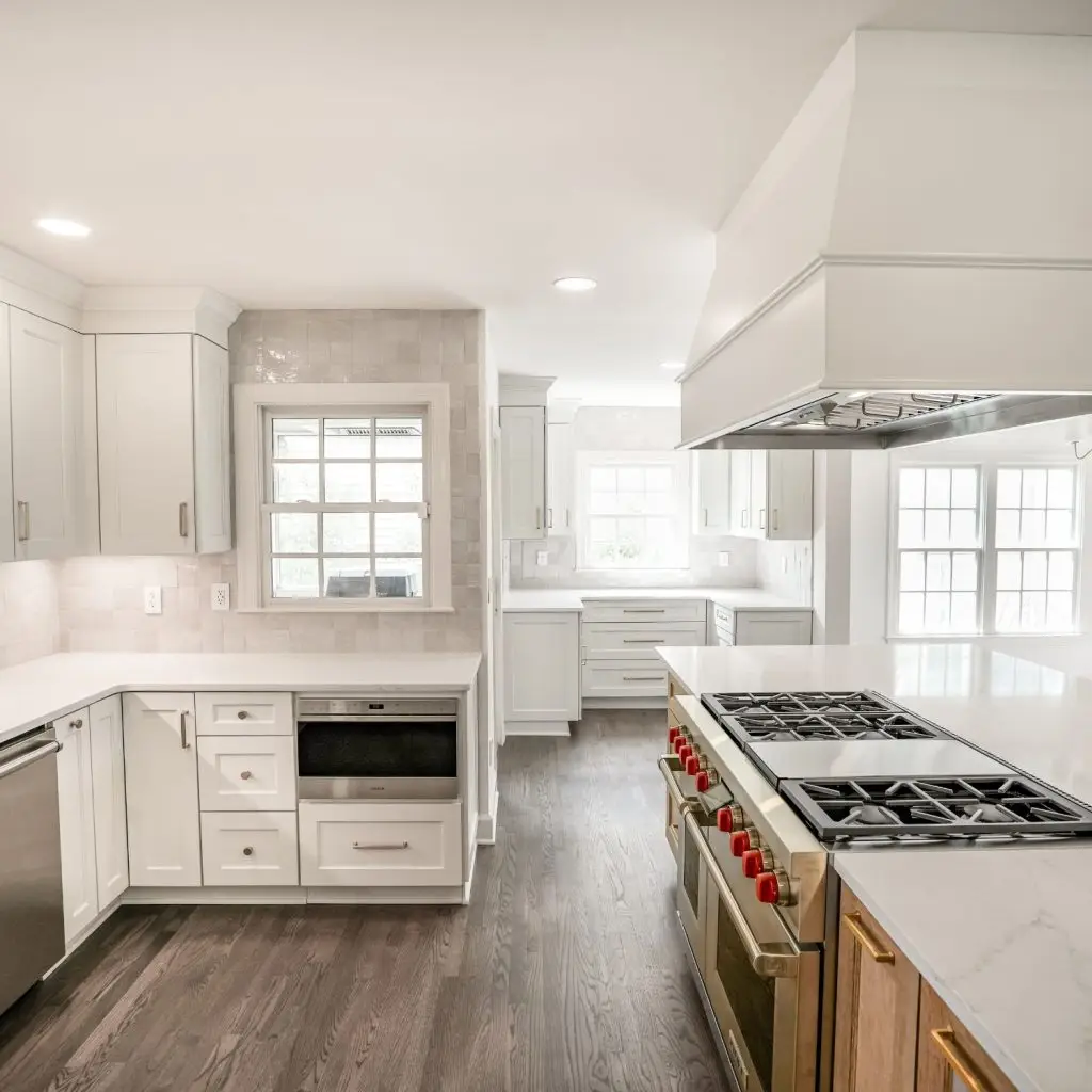 Bright, modern kitchen remodel featuring white cabinetry, marble countertops, high-end stainless steel appliances, and natural light flooding through multiple windows—showcasing expert home renovation in Mountain Brook, AL.