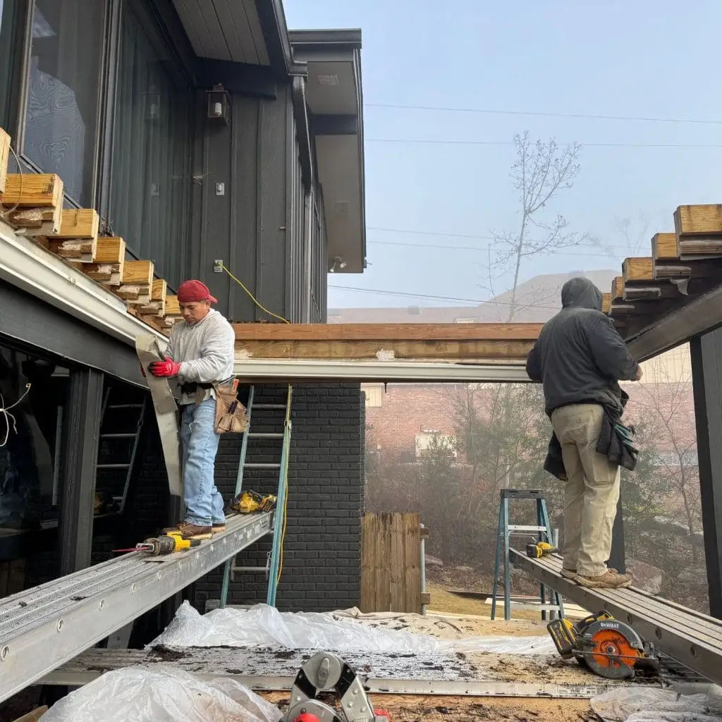 Two contractors working on a second-story deck replacement, highlighting code-compliant construction in Hoover, AL where deck permits are always required.